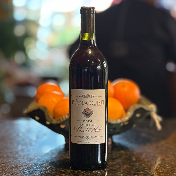 Bottle of Bonacquisti 2024 American Pinot Noir with oranges in the background