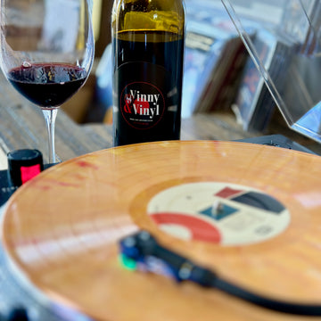 A bottle of Vinny & Vinyl wine and Dojo Cuts playing on the turntable.