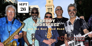 Promotional image of Freddy Rodriguez and the Soul Food Band with instruments and a clock tower in the background.