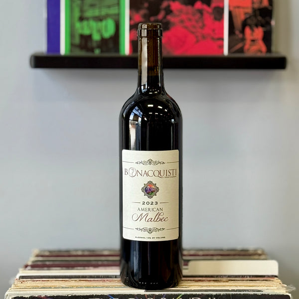 Wine bottle labeled Bonacquisti Malbec on a wooden surface with a blurred background